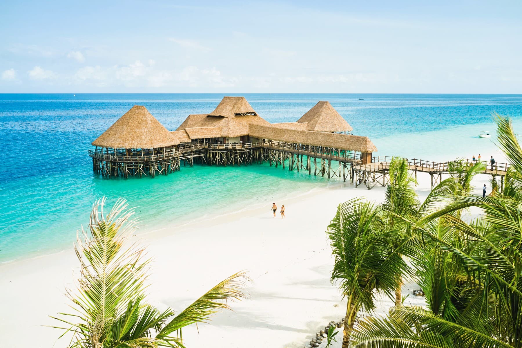 Praia de Zanzibar com areia branca, mar azul-turquesa e palmeiras